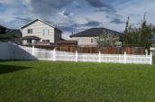 rising vinyl picket fence around home backyard