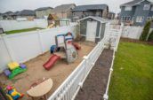 kinsmen vinyl picket fence enclosing shed and play area in home backyard