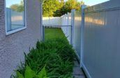 A newly installed white vinyl fence in a lush green backyard